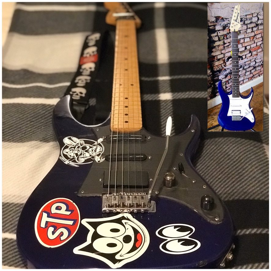 The $79 blue Ibanez GIO, modded with stickers and a roasted maple neck, with an inset of it stock