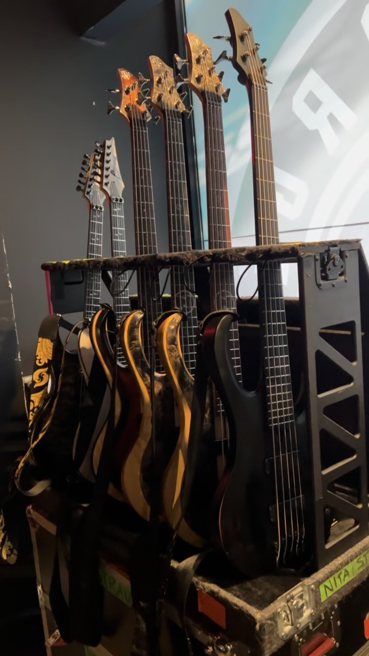 Guitars and basses lined up on the backstage rack